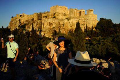 Turistas en la Colina de Ares, en Atenas, con la Acrópolis al fondo.