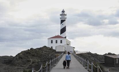 Una mujer y su perro junto al faro de Favàritx, en Menorca.