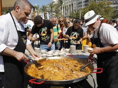 Dos cocineros emplatan una paella de marisco en la plaza del Ayuntamiento de Valencia.