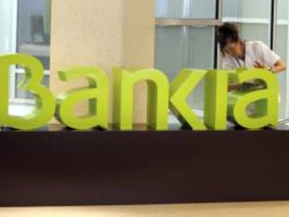 Una operaria limpia el logo de Bankia en una oficina. EFE/Archivo