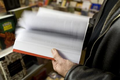 Un lector hojea un libro en una librería de Barcelona.