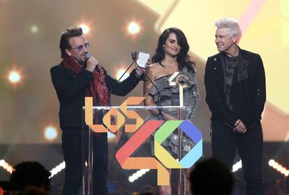 Bono (i) y Adam Clayton, integrantes del grupo U2, reciben el premio Golden Music Awards de la mano de Penelope Cruz.