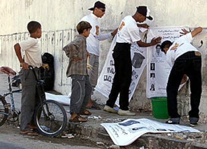 Varios jóvenes colocan carteles con propaganda electoral en una calle de Casablanca. ESCENA