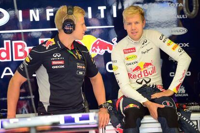 Sebbastian Vettel conversa con un mecánico de Red Bull en boxes.