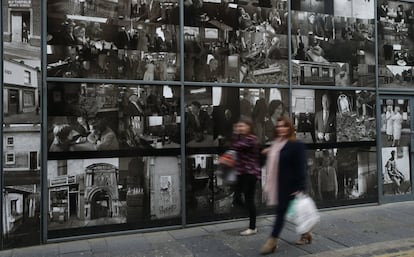 Los recuerdos del pasado están por todas partes. Murales y monumentos conmemorativos a las víctimas del conflicto armado se mezclan con aquellos dedicados a la paz. En la imagen, dos mujeres caminan frente a un montaje fotográfico que narran la historia de Belfast en imágenes.