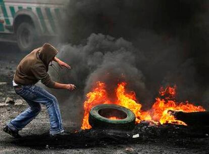 Un palestino aviva el fuego de una barricada en el campo de refugiados de Shuafat, en Cisjordania.