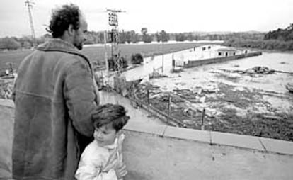 Un hombre y un niño, vecinos de una barriada cordobesa, observan la inundación provocada por la crecida del río.