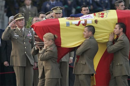 El Rey y el Príncipe saludan al paso de un ataúd, cubierto con la bandera y coronado con la boina del fallecido.