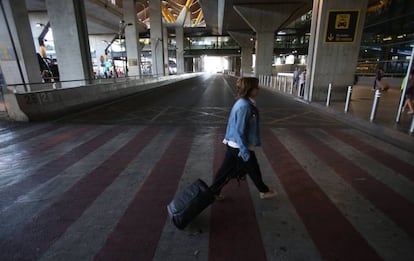 Una mujer empuja una maleta a su llegada al aeropuerto de Barajas durante la jornada de huelga de los taxistas madrileños.