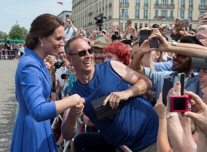 Los duques de Cambridge han alternado en la jornada de hoy protocolo y cercanía. En la imagen, Kate Middleton saluda y se fotografía con algunos berlineses que se han acercado a la Puerta de Brandenburgo para ver a los duques de Cambridge en su visita al país.