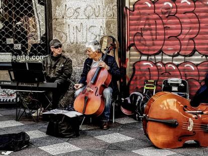 Dos músicos tocan al final de la calle del Arenal, junto a la plaza de Ópera.