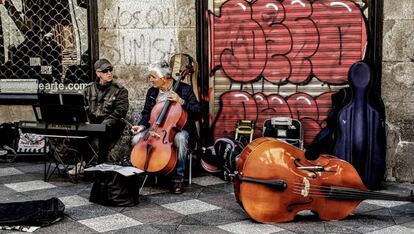 Dos músicos tocan al final de la calle del Arenal, junto a la plaza de Ópera.