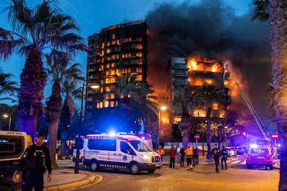 Ambulancias y agentes de policía frente al edificio en llamas.