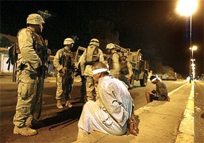 Soldados de Estados Unidos vigilan a dos detenidos en una carretera cerca de Tikrit.