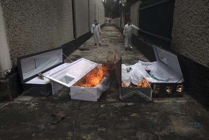 Dos empleados del tanatorio de Iztapalapa (Ciudad de México) queman los ataúdes de víctimas del coronavirus.