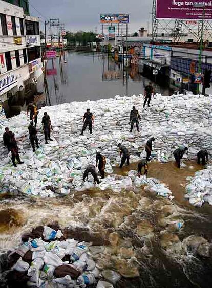 Los soldados construyen un dique con sacos para contener el agua.