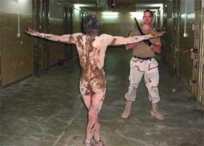 Un preso iraquí posa desnudo y con los pies atados ante un soldado estadounidense en la prisión de Abu Ghraib. Su cuerpo ha sido rociado con excrementos.