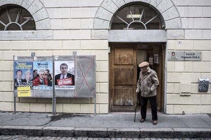 Un hombre mira tres carteles electorales después de votar, en Lyon.