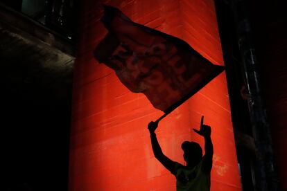 Un seguidor de Lula festeja con una bandera y la mano izquierda en forma de "L" en honor al ganador de los comicios. 