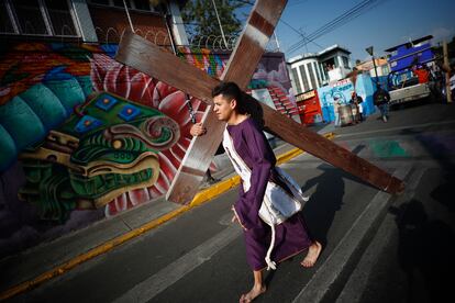 Un nazareno carga una cruz sobre sus hombros en Iztapalapa, durante la representación de la Pasión de Cristo en Ciudad de México.
