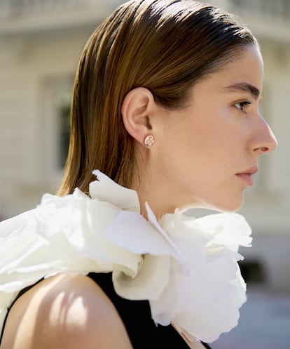 La actriz lleva mono de seda, collar de flores y pendiente de botón color Blossom Sun de oro rosa y nácar rosa, todo de LOUIS VUITTON.