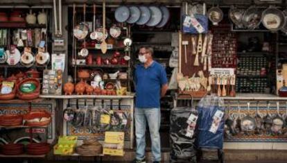 Un comerciante espera a las puertas de su comercio a la espera de clientes.