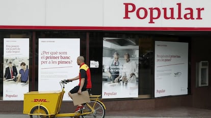 Un repartidor pasa por delante de una oficina del Banco Popular, en Barcelona.