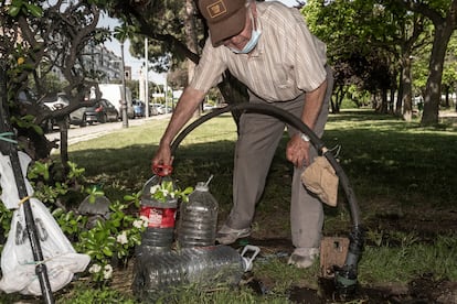 Serafín Bonilla llena las garrafas de agua con las que luego riega la pequeña parcela de cultivo en Alcorcón. 


