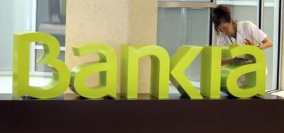 Una operaria limpia el logo de Bankia. 