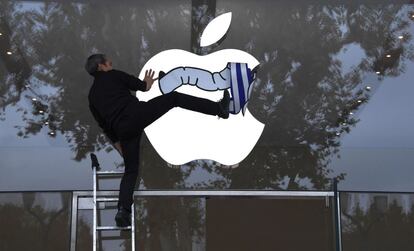 Un activista de la Asociación para la Tributación de las Transacciones financieras y la Acción Ciudadana (ATTAC) coloca una pegatina de un gusano sobre el logo de Apple, en protesta por la evasión de impuestos de la empresa coincidiendo con el lanzamiento del nuevo iPhone X en Aix-en-Provence (Francia)
