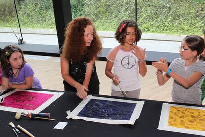 La artista textil Virginia Ameztoy explica a unas niñas la técnica del <i>discharge </i>en los pañuelos.