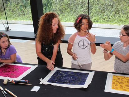 La artista textil Virginia Ameztoy explica a unas niñas la técnica del <i>discharge </i>en los pañuelos.