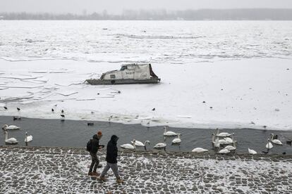 Dos personas pasean cerca de un barco atrapado por el hielo, cerca de Belgrado (Serbia).