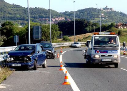 Una grúa pasa junto a varios turismos accidentados y abandonados en un arcén del País Vasco.