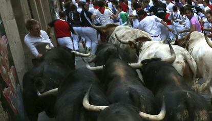 Un mozo es embestido, en la curva de Mercaderes de Pamplona, por uno de los toros de la ganadería madrileña de Victoriano del Río que han protagonizado el cuarto encierro, el más rápido de los sanfermines 2013, que ha finalizado en 2 minutos y 11 segundos, y que ha sido muy peligroso, ya que por su velocidad han atropellado a muchos mozos durante el recorrido.