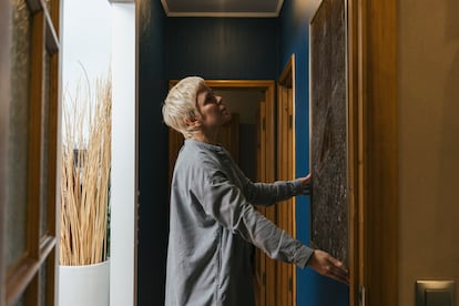 Una mujer colgando un cuadro en su casa.