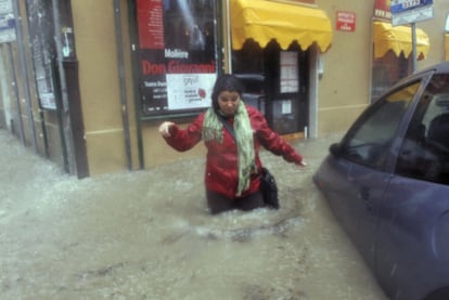 Una mujer trata de caminar por una calle inundada en Génova, ayer.