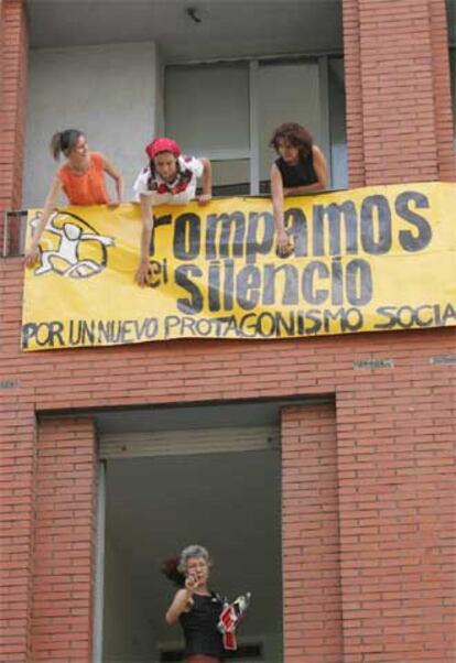 Varias mujeres cuelgan una pancarta con el lema <i>Rompamos el silencio</i> tras <i>okupar</i> el edificio.