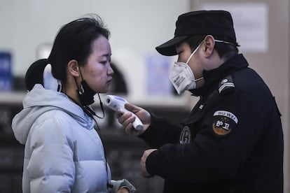 Personal de seguridad toma la temperatura a una pasajera en la estación de tren de Wuhan (China), este jueves, tras entrar en vigor el veto anunciado por las autoridades locales. Hasta nuevo aviso sus 11 millones de habitantes no pueden salir, ni tampoco entrar. Wuhan es una ciudad cerrada.