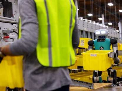 Un operario de Amazon junto a un robot humanoide en un almacén de la compañía.