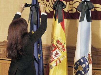 Una trabajadora de la Xunta ata lazos negros a las banderas en el Pazo de Raxoi.