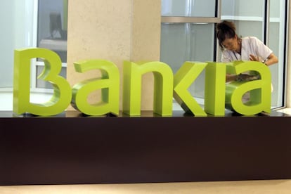 Una operaria limpia el logo de Bankia en la sede de la empresa.