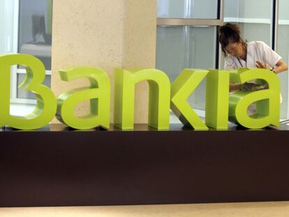 Una operaria limpia el logo de Bankia en la sede de la empresa.