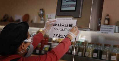 El encargado de un negocio de alimentación en Terrassa (Cataluña) coloca un cartel de advertencia en el mostrador.