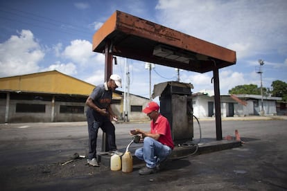 Dos hombres rellenan de gasolina unos bidones en Chivacoa (Venezuela), el 13 de octubre de 2019.