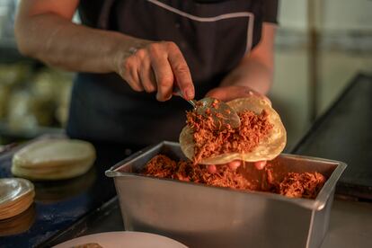 Una cocinera prepara un taco de chilorio.