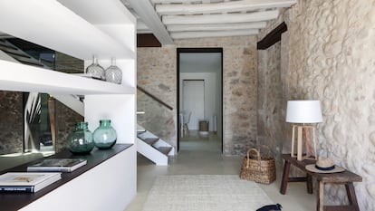 La entrada comunica con el salón principal. El mueble separador blanco está hecho a medida y enmarca la chimenea. Es un diseño de la arquitecta Glòria Duran, responsable de la restauración de la masía.