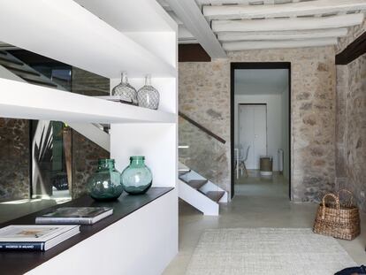 La entrada comunica con el salón principal. El mueble separador blanco está hecho a medida y enmarca la chimenea. Es un diseño de la arquitecta Glòria Duran, responsable de la restauración de la masía.