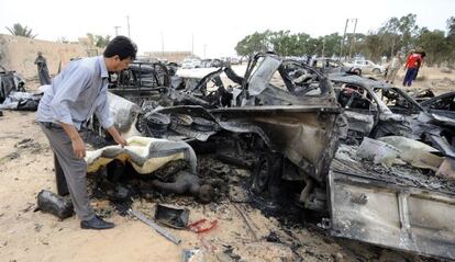 Un hombre cubre un cadáver quemado en el lugar en el que la OTAN atacó al convoy que trasportaba a Gadafi en Sirte.
