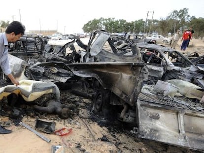 Un hombre cubre un cadáver quemado en el lugar en el que la OTAN atacó al convoy que trasportaba a Gadafi en Sirte.
